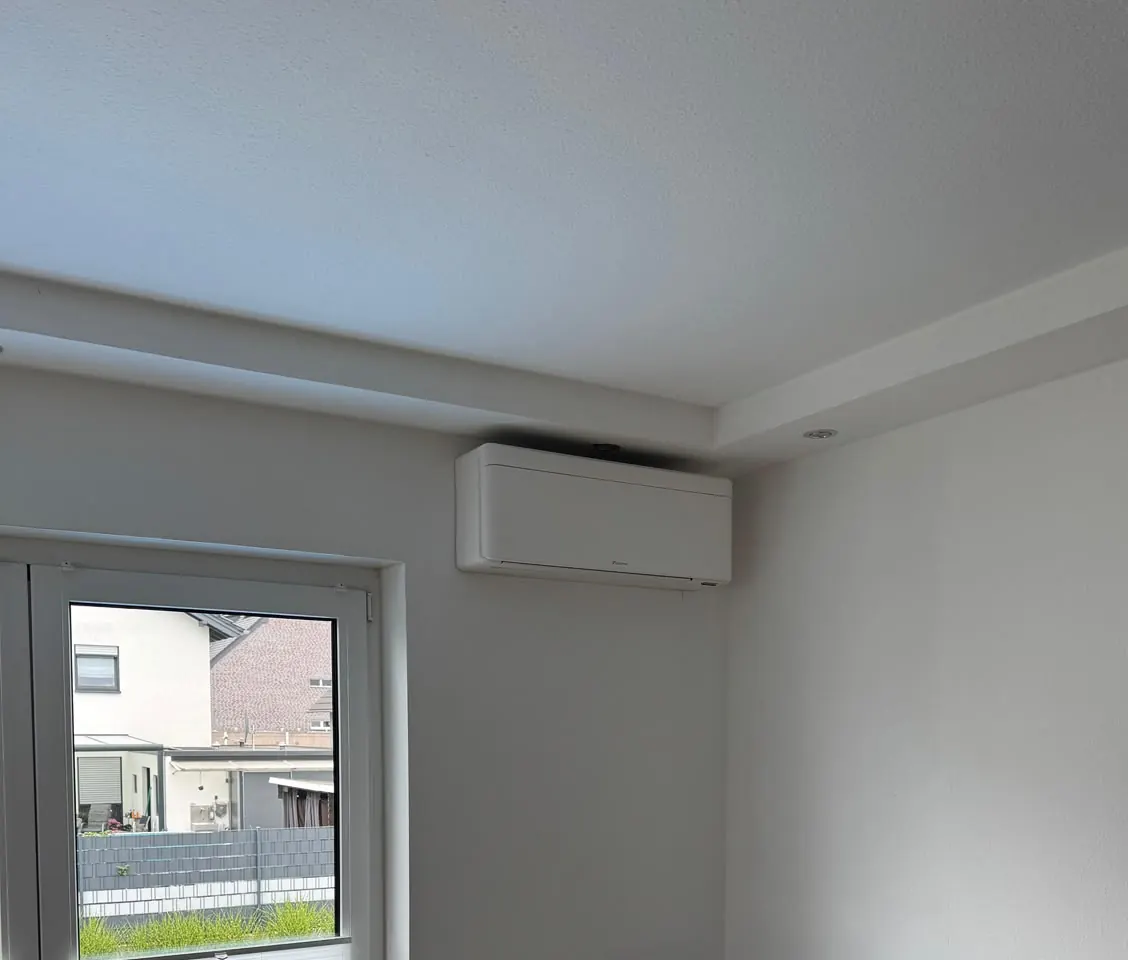 Von DBO montiertes Innengerät hoch an der Wand über einer Terrassentür in einem hellen Wohnraum